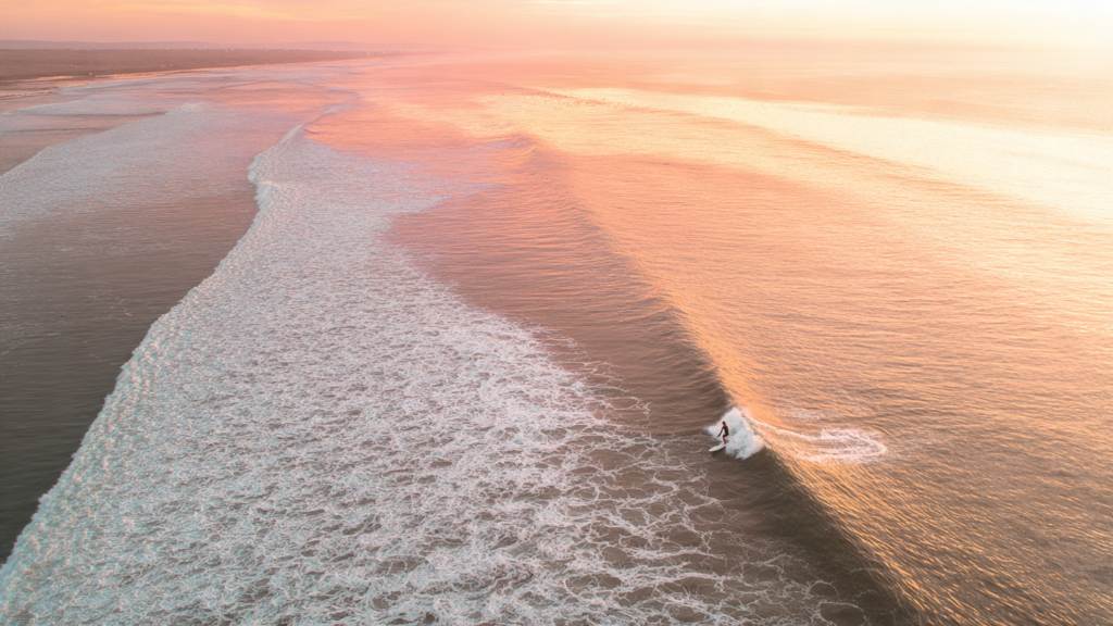 Surfer riding endless left point break at Chicama during golden hour sunset in Northern Peru