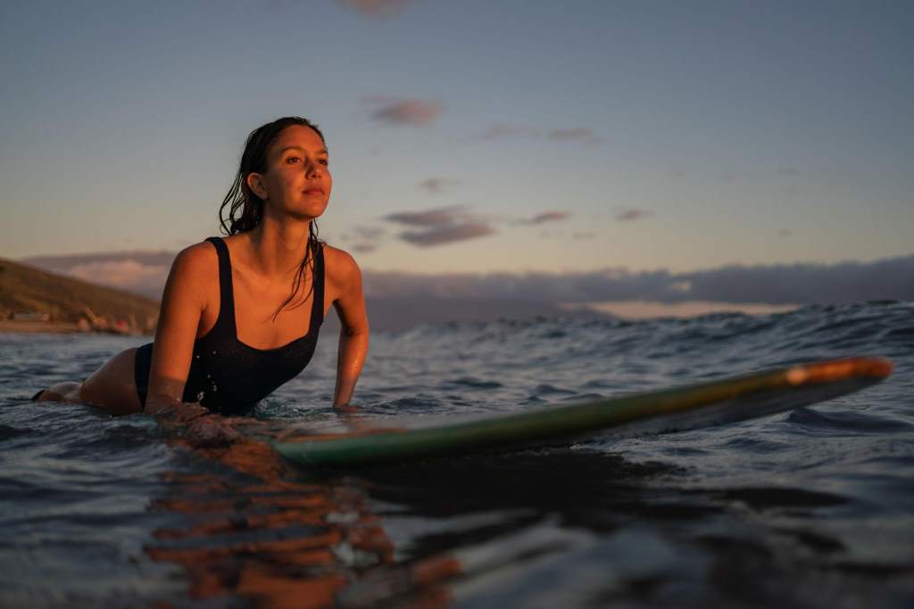 Female surfer paddles through tropical waters