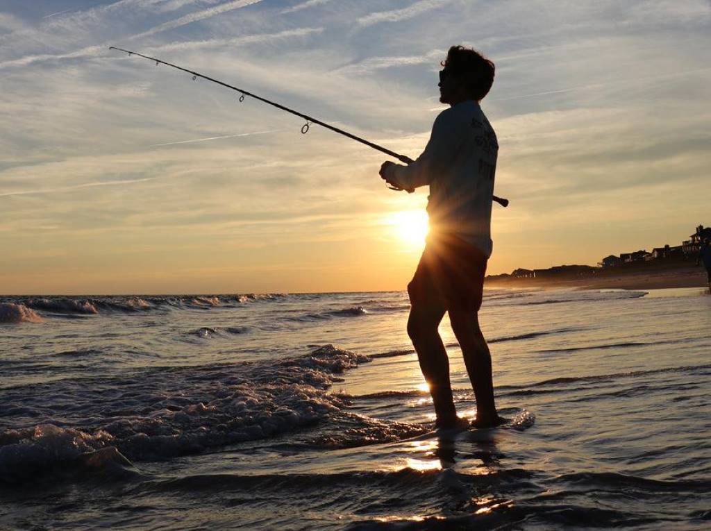 Surf fishing rig setup on sandy beach with rods and ocean waves