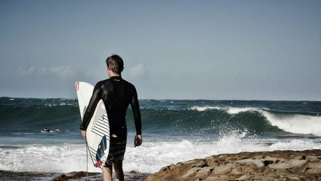 Man wearing surfing rash guard riding a wave for sun protection and comfort