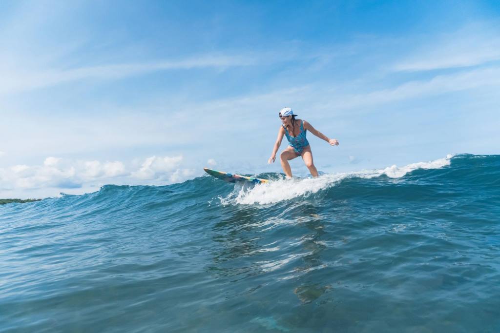 woman in swimming suit surfing in ocean