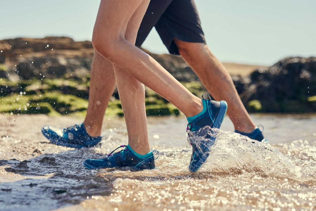 Person wearing water shoes walking on wet rocks while surfing and swimming comfortably