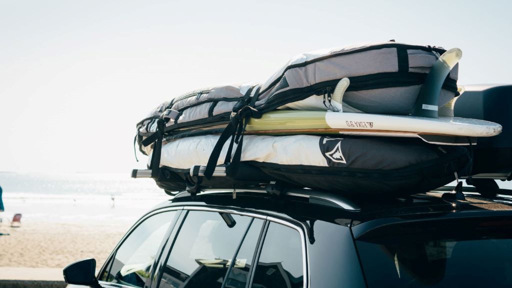 Surfboard secured to a car roof rack for safe transport along a California coastal highway