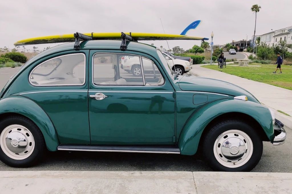 Surfer loading a surfboard onto a car rack before heading to a California beach session