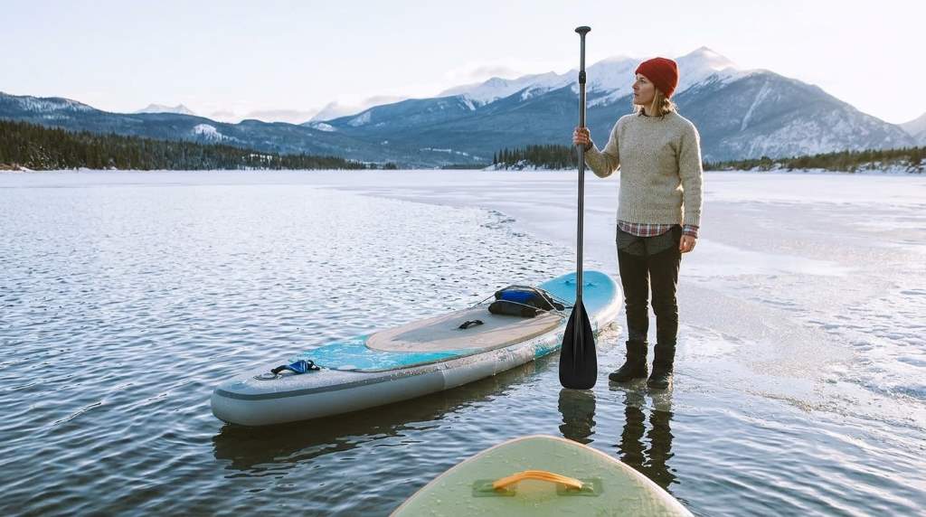 Paddler adjusting cam lock collar on aluminum SUP paddle on lakeshore